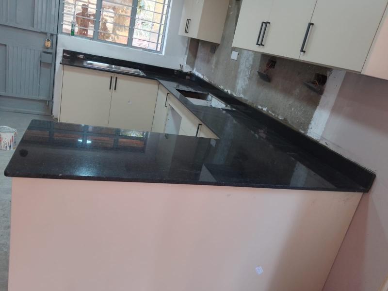 In Kiambu Nairobi: Absolute Black Granite countertops paired with sleek, wood-finish cabinetry and a deep, under-mounted double-bowl stainless steel sink.