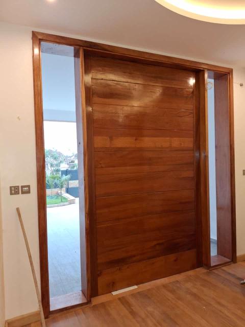 Master Joinery: Solid Mahogany Doors & Frames
A door is the first thing you touch when entering a room, and it sets the tone for the entire experience. For this project, "standard" was not an option.

The Choice: We installed custom-fabricated solid mahogany doors with matching wide-profile frames. As seen in the main living area, we used a massive horizontal-slat mahogany sliding/pivot door.